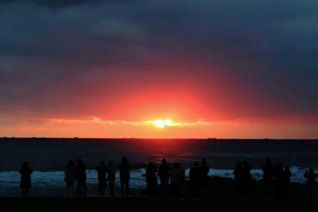 silhouette of people standing on beach during sunset